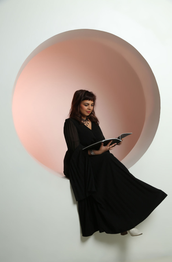 Neelu Agarwal reading, framed by a soft blush halo